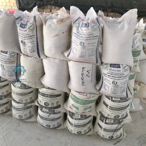 نمای نزدیک از چند کیسه 25 و 30 کیلویی پودر سفید قرار گرفته روی یکدیگر در فضای داخلی کارگاه