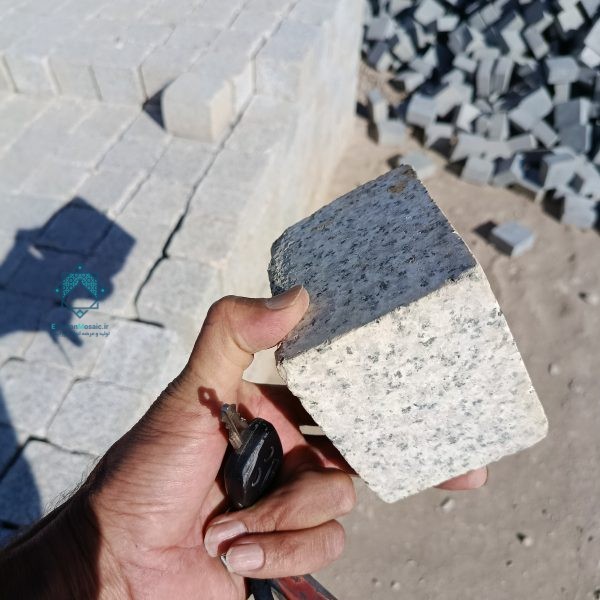 سنگ کوبیک گرانیت خاکستری در دست یک فرد برای نمایش ضخامت جهت راهنمایی خرید سنگ کوبیک گرانیت مشکی
