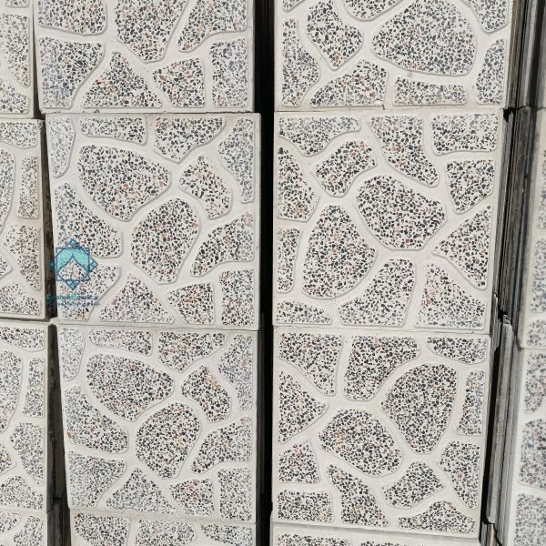 نمای نزدیک از چند موزاییک حیاطی پلنگی سنگ سفید زمینه قرمز که بر روی دسته قرار گرفته‌اند