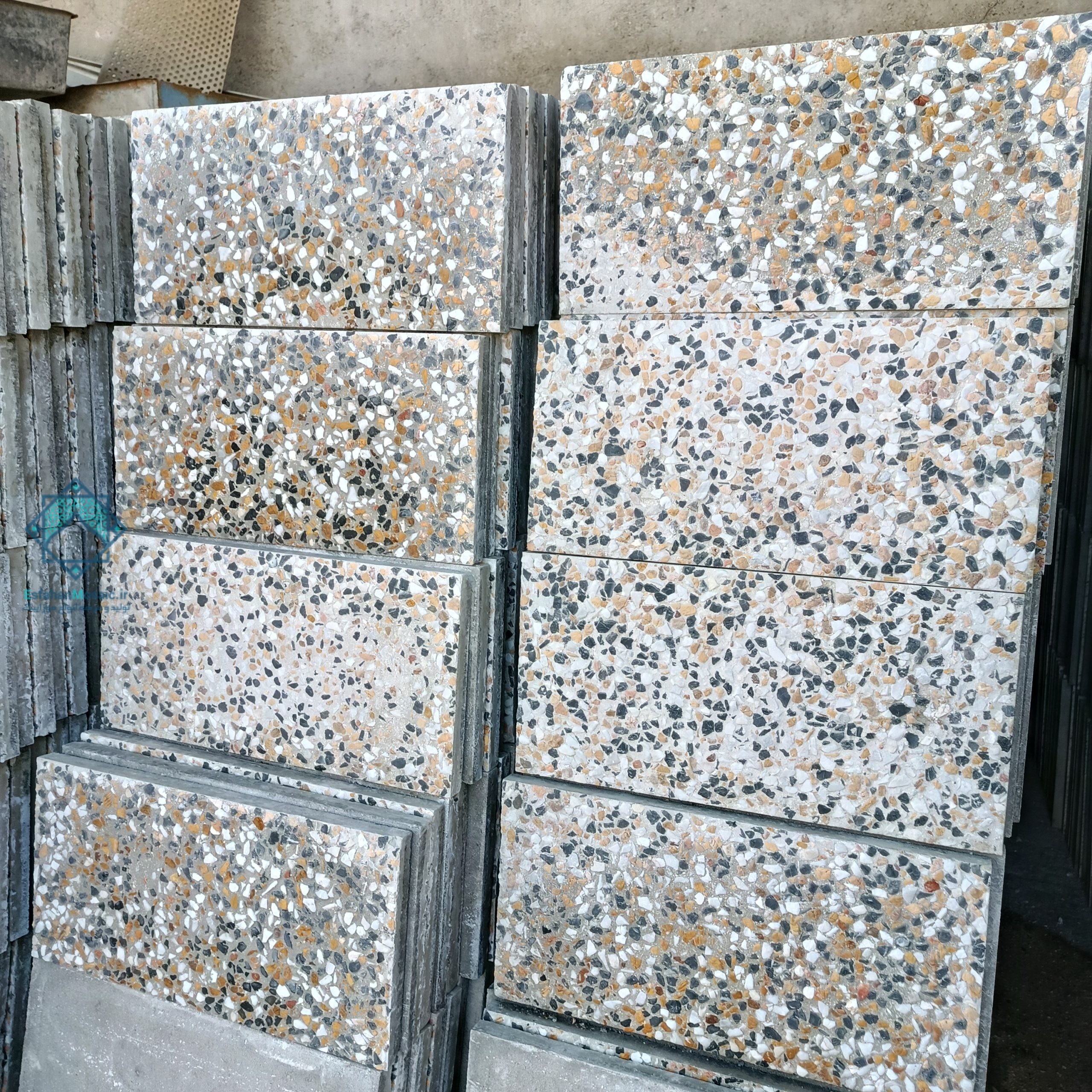تصویر دستهای از موزاییکهای واش بتن 30 در 60 ترکی که بر روی هم قرار گرفتهاند